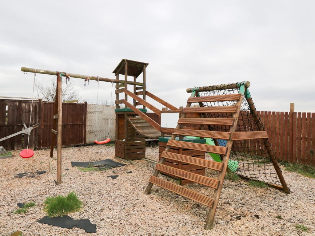 Lawned garden, shared patio with furniture, and children's play area