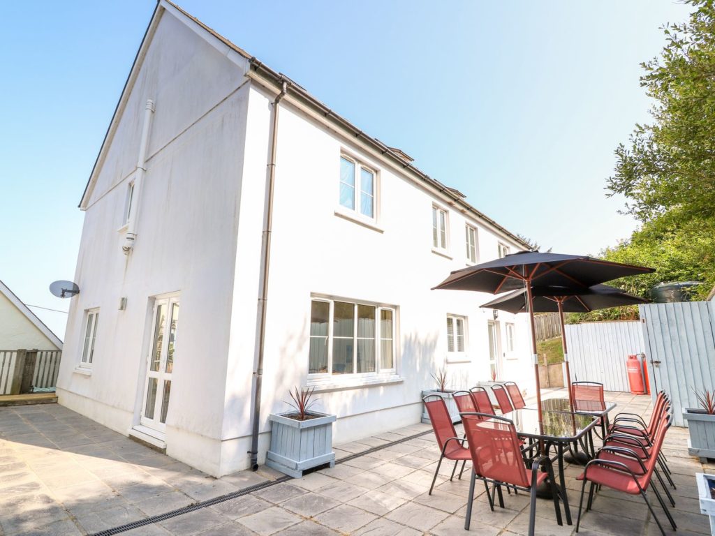 Enclosed Rear patio area with garden furniture and sea-facing front veranda with seating